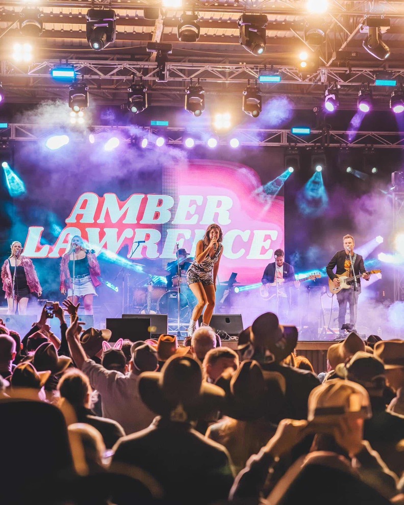 Amber Lawrence performing to a crowd in cowboy hats at the Deni Ute Muster